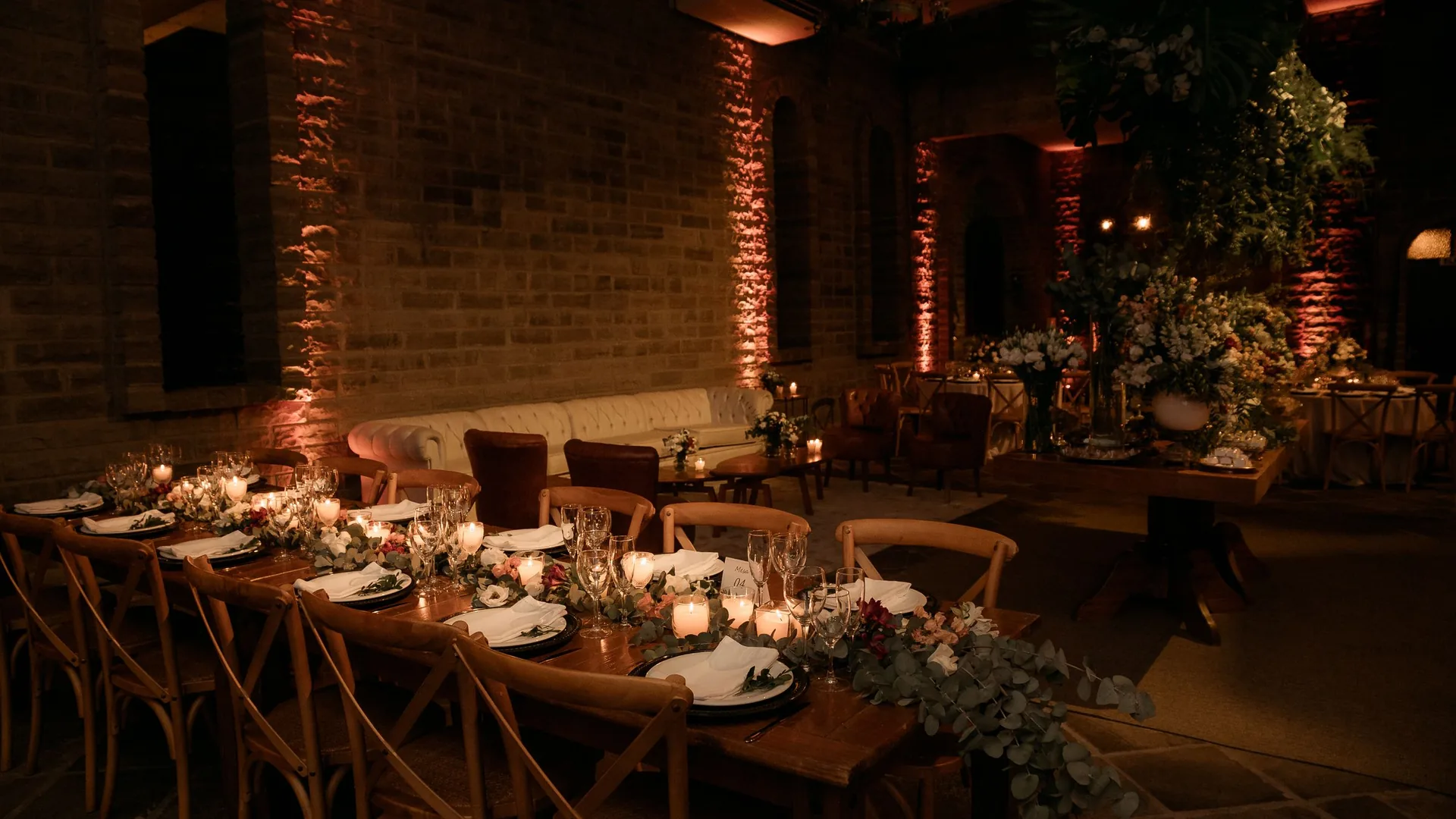 A long candlelit dinner table set for a group evening